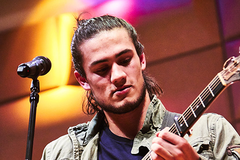 Guitarist looks down as he performs on stage